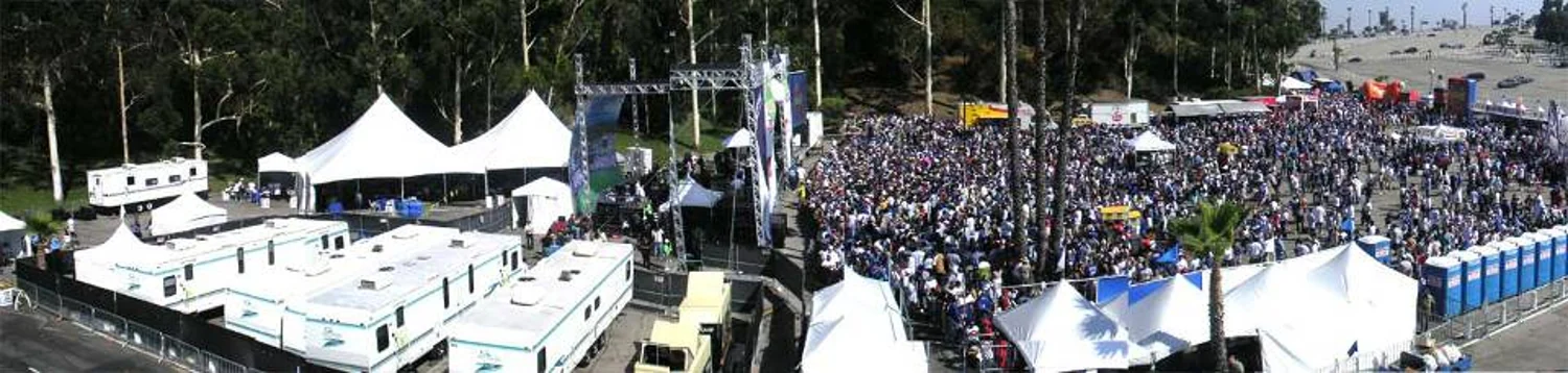 Panoramic view of a large outdoor event with crowds, tents and a stage