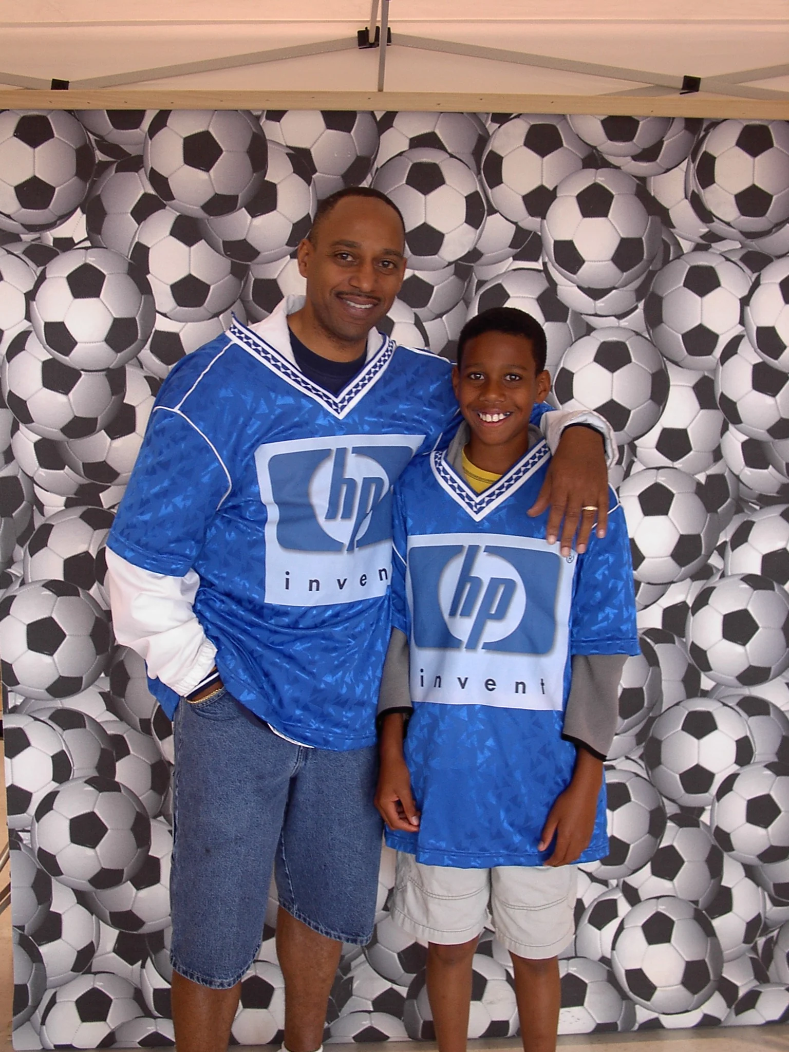 Two participants wearing HP jerseys in front of a soccer-ball backdrop