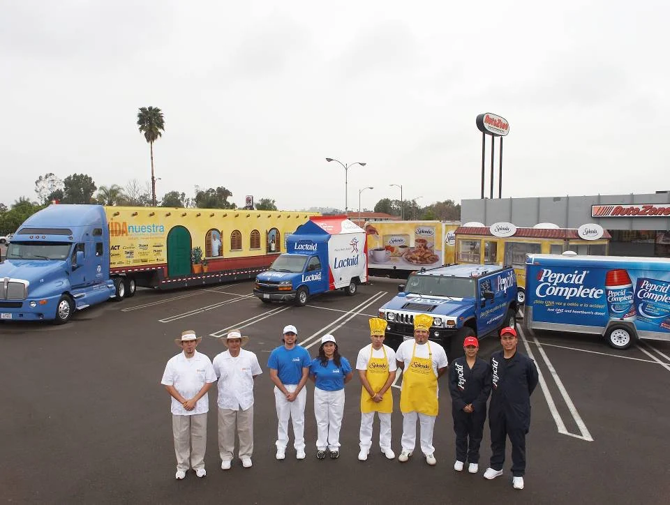 Field team standing in front of branded roadshow vehicles