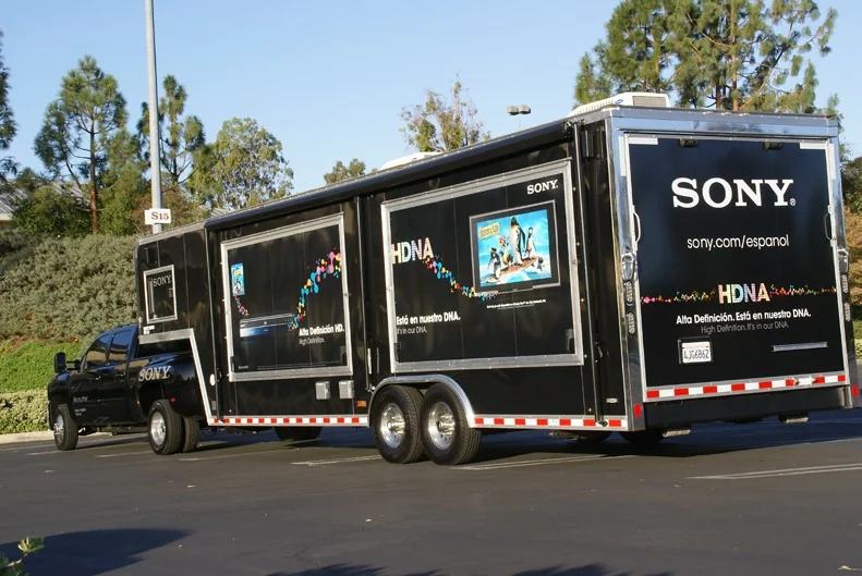 Rear three-quarter view of the Sony trailer beside a tree-lined parking lot