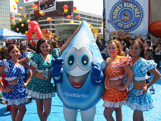 Sparkletts water-drop mascot with performers at an outdoor event